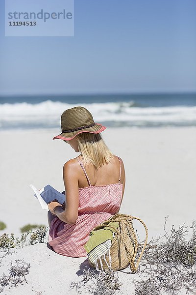Frau beim Lesen eines Buches am Strand
