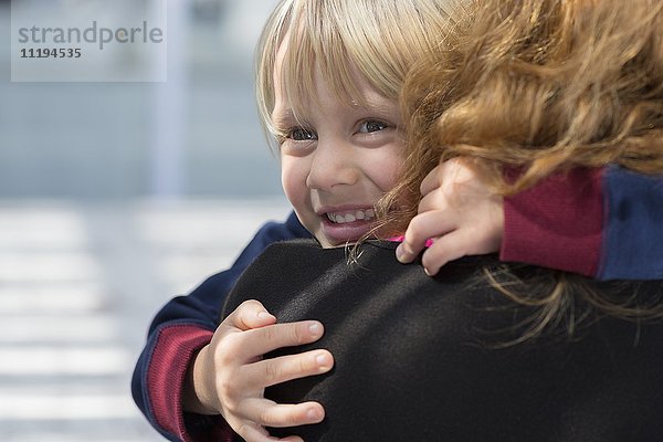 Ein glücklicher kleiner Junge  der seine Mutter umarmt.