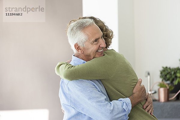 Glücklicher älterer Mann  der seinen jugendlichen Enkel umarmt.
