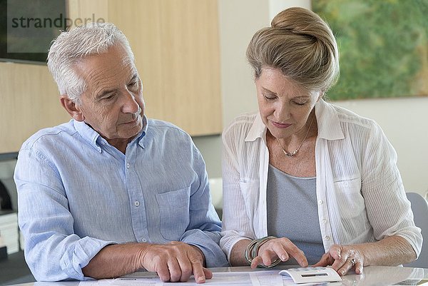 Seniorenpaar beim Sortieren von Rechnungen zu Hause