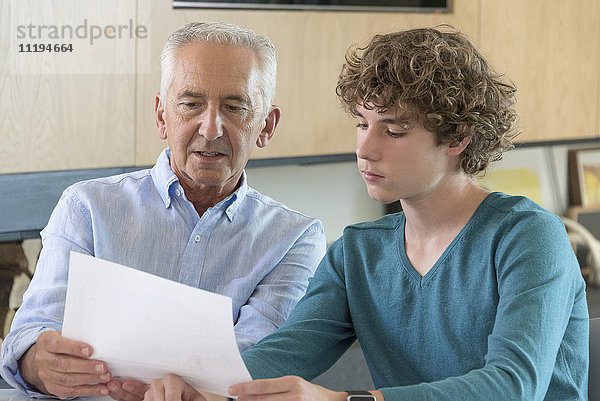 Älterer Mann macht Papierkram mit Enkel im Wohnzimmer
