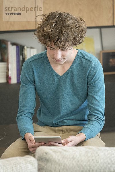 Teenager-Junge mit einem digitalen Tablett im Wohnzimmer