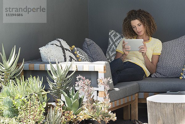 Frau auf einer Couch sitzend mit einem digitalen Tablett