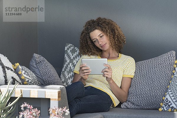 Frau auf einer Couch sitzend mit einem digitalen Tablett