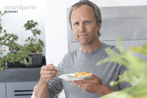 Porträt eines reifen Mannes beim Essen von Obstsalat
