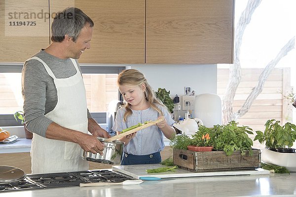 Kleines Mädchen und ihr Vater bereiten das Essen in der Küche zu.