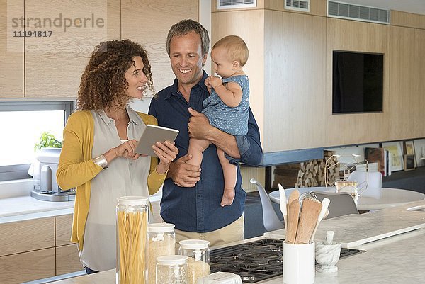Paar mit digitalem Tablett mit ihrer Tochter in der Küche