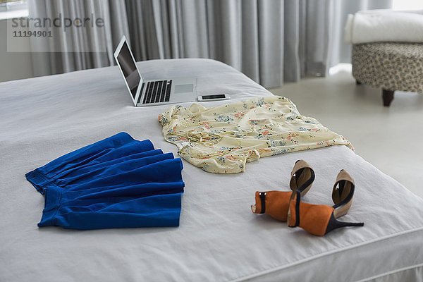 Kleidung und Laptop auf dem Bett