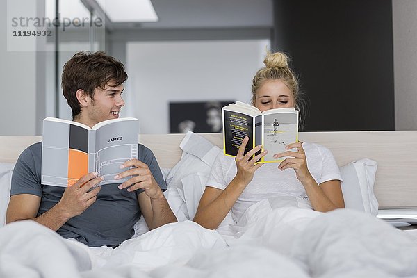 Junges Paar liest Bücher auf dem Bett