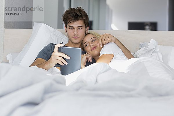 Junges Paar schaut sich Film auf digitalem Tablett an
