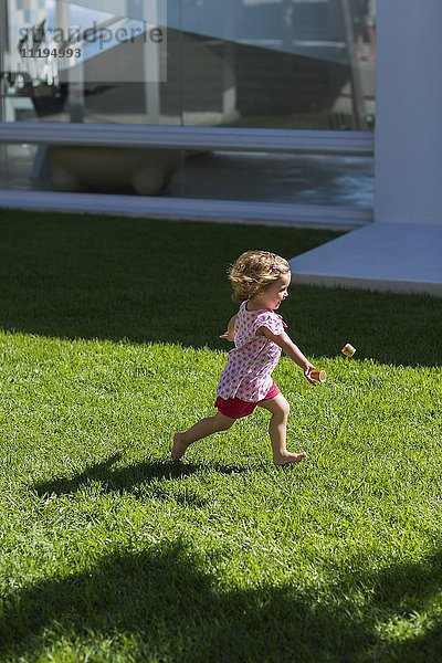 Profil eines kleinen Mädchens  das auf Rasen spielt