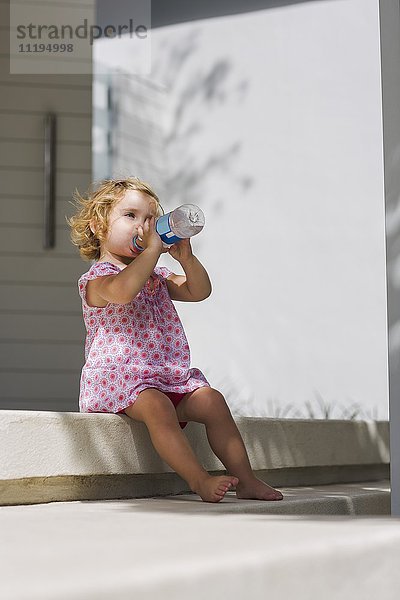 Kleines Mädchen trinkt Wasser aus einer Flasche