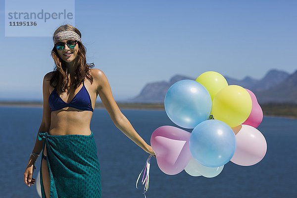 Fröhliche junge schöne Frau mit Luftballons