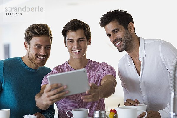 Nahaufnahme von drei glücklichen jungen Männern  die Selfie mit einem digitalen Tablett nehmen.