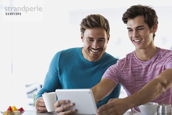 Nahaufnahme von zwei glücklichen jungen Männern  die Selfie mit einem digitalen Tablett nehmen.