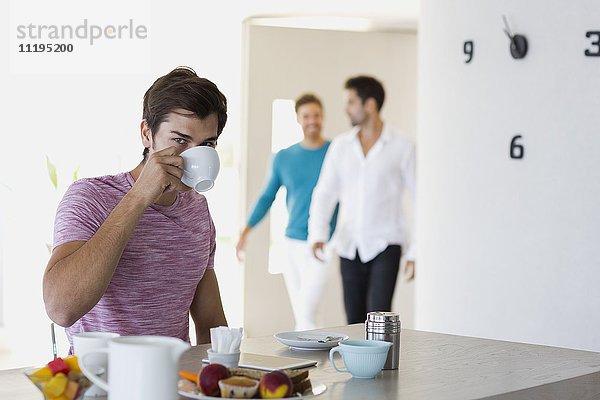 Nahaufnahme eines jungen Mannes beim Frühstück mit seinen Freunden im Hintergrund