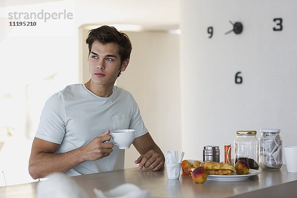 Nahaufnahme eines attraktiven jungen Mannes beim Kaffeetrinken
