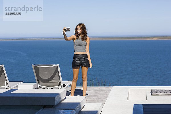 Schöne junge Frau  die Selfie mit einem Smartphone nimmt.