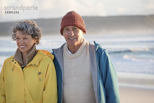 Glückliches älteres Paar am Strand stehend