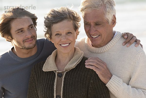 Porträt einer glücklichen Familie am Strand stehend