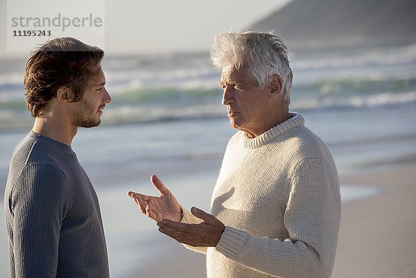 Glücklicher Vater und Sohn im Gespräch am Strand