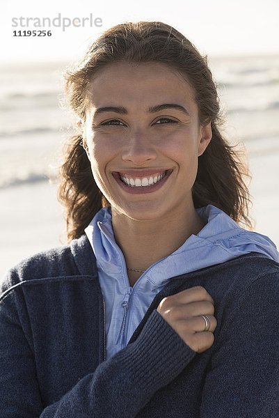 Hübsche junge Frau  die am Strand lächelt.