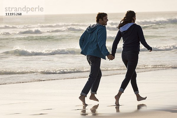 Ein glückliches junges Paar läuft am Strand.