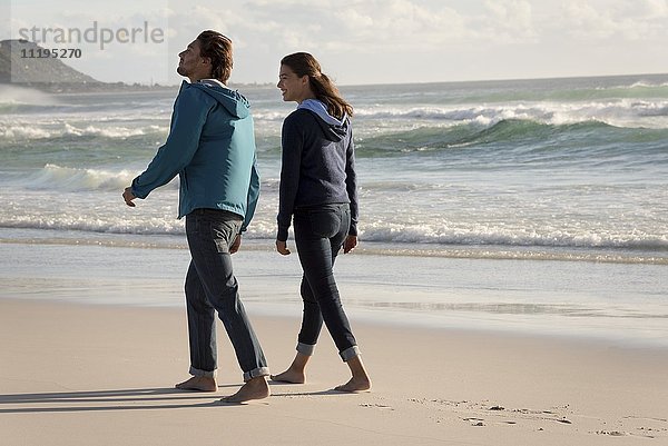 Ein glückliches junges Paar geht am Strand spazieren.