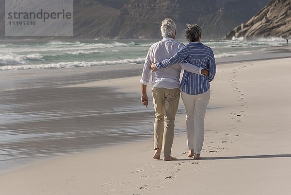 Rückansicht des Seniorenpaares beim Spaziergang am Strand