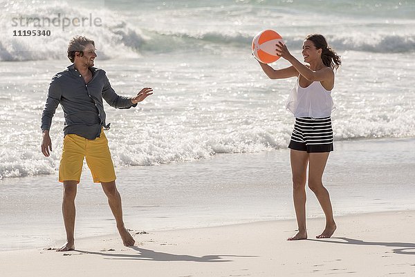 Glückliches junges Paar beim Spielen mit einem Strandball