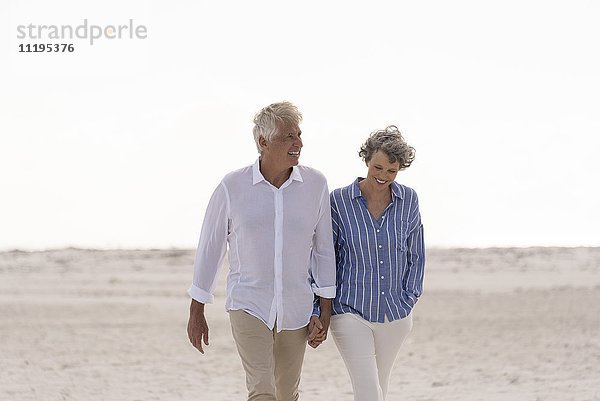 Fröhliches Senior-Paar beim Spaziergang am Strand