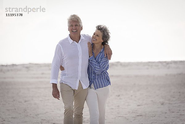 Fröhliches Senior-Paar beim Spaziergang am Strand