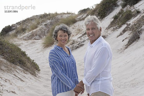 Glückliches älteres Paar am Strand stehend