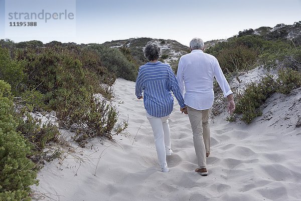 Rückansicht des Seniorenpaares beim Spaziergang am Strand