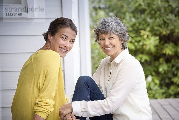 Porträt einer glücklichen Mutter  die mit ihrer erwachsenen Tochter auf der Veranda sitzt.
