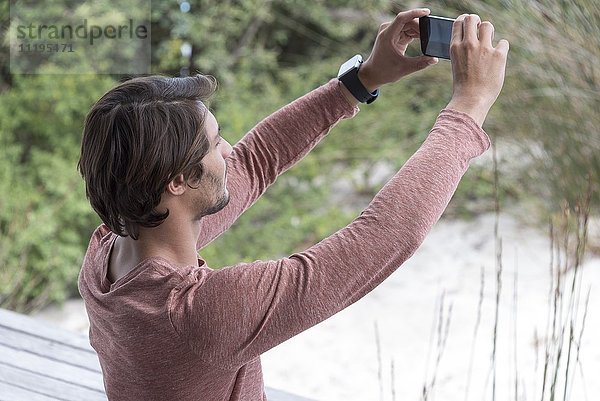 Junger Mann  der einen Selfie mit Fotohandy nimmt