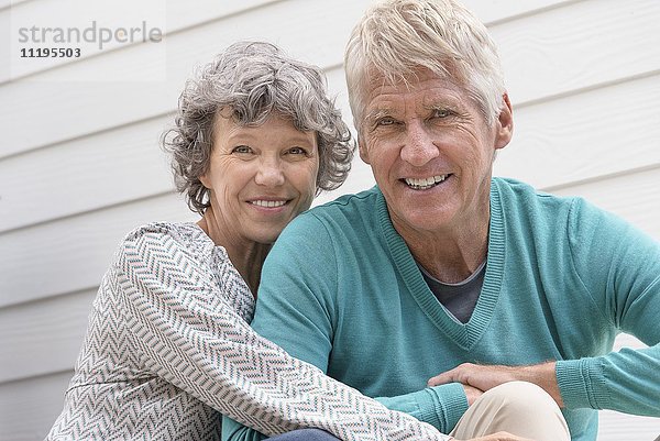 Glückliches Senior-Paar sitzt vor dem Haus