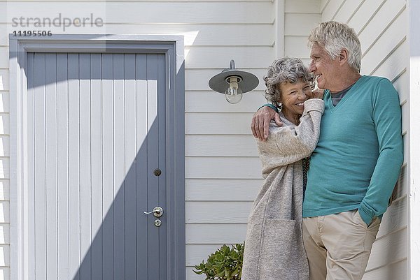 Romantisches Seniorenpaar  das sich außerhalb des Hauses umarmt