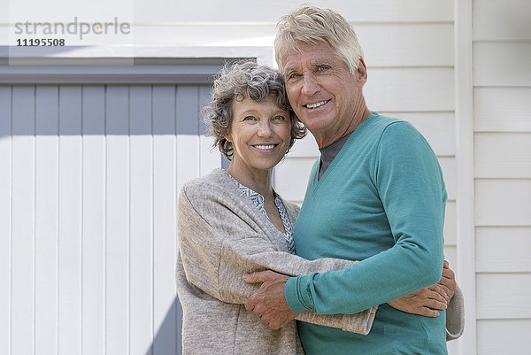Liebende ältere Paare  die sich außerhalb des Hauses umarmen