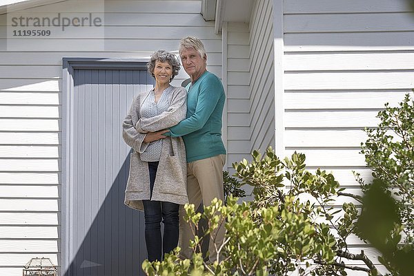 Glückliches Seniorenpaar  das sich außerhalb des Hauses umarmt.