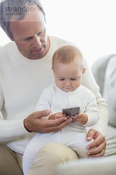 Glücklicher Vater und seine kleine Tochter beim Spielen mit dem Handy auf der Couch