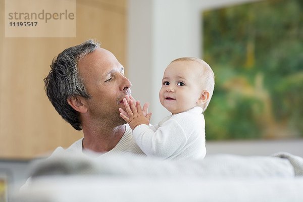 Glücklicher Vater spielt mit seiner süßen kleinen Tochter im Wohnzimmer