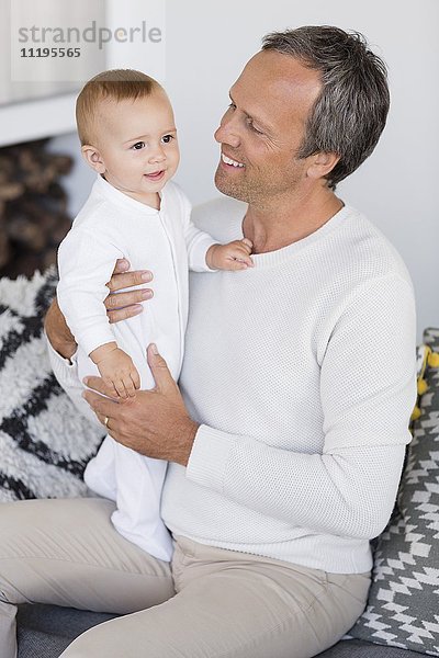 Glücklicher Vater mit seiner süßen kleinen Tochter  die im Wohnzimmer sitzt