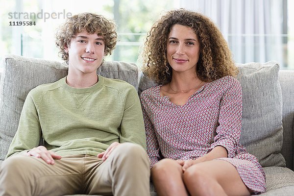 Porträt einer glücklichen Mutter und eines glücklichen Sohnes auf der Couch im Wohnzimmer