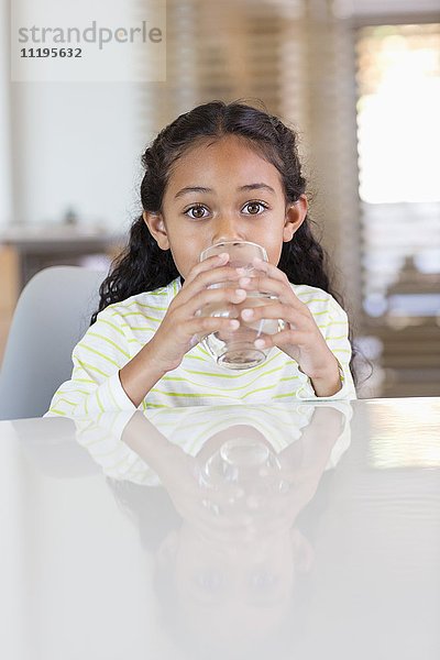 Kleines Mädchen  das zu Hause ein Glas Wasser trinkt.