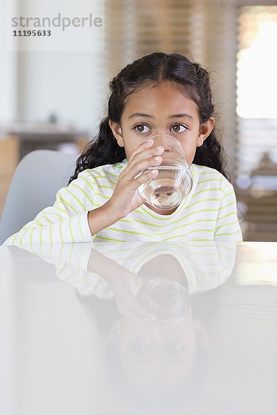 Kleines Mädchen  das zu Hause ein Glas Wasser trinkt.