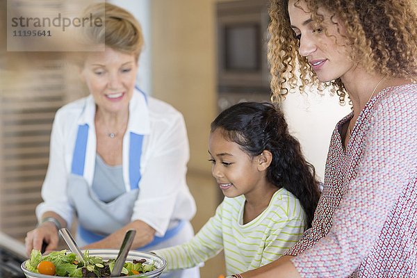 Seniorin mit Tochter und Enkelin bei der Zubereitung von Speisen in der Küche