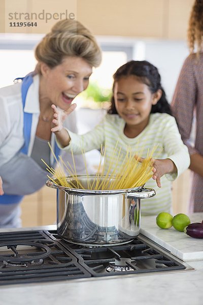 Seniorin mit Tochter und Enkelin bei der Zubereitung von Speisen in der Küche
