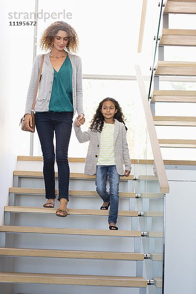 Glückliche Mutter und Tochter halten sich an der Treppe.