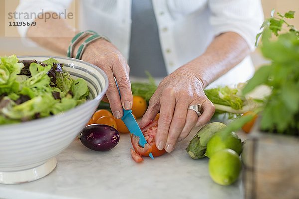 Seniorin beim Schneiden von Gemüse in der Küche